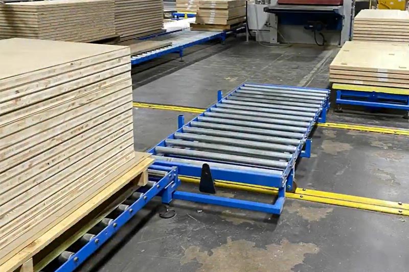 Sistema di trasporto a rulli a gravità per il trasporto di pile di fogli di legno