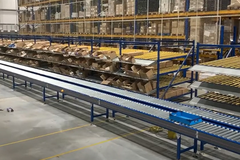 Sistema di trasporto a rulli per magazzino azionato da albero motore